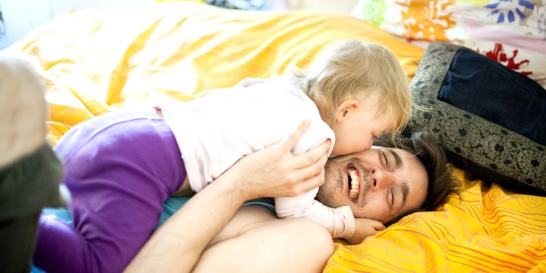 Pappa ligger i soffan och leker med sitt lilla barn